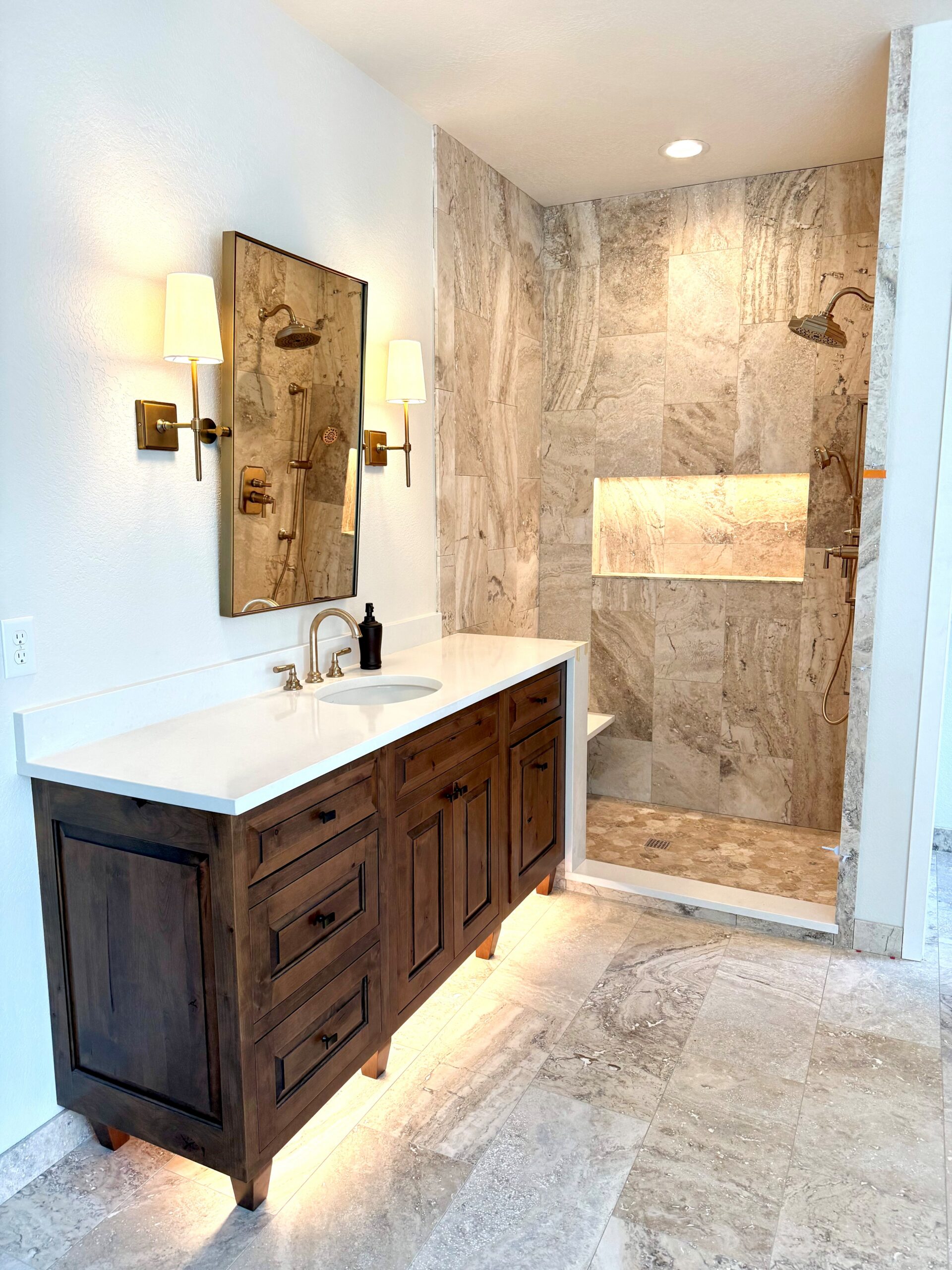 Dark wood bathroom vanity beside a stone-tile walk-in shower