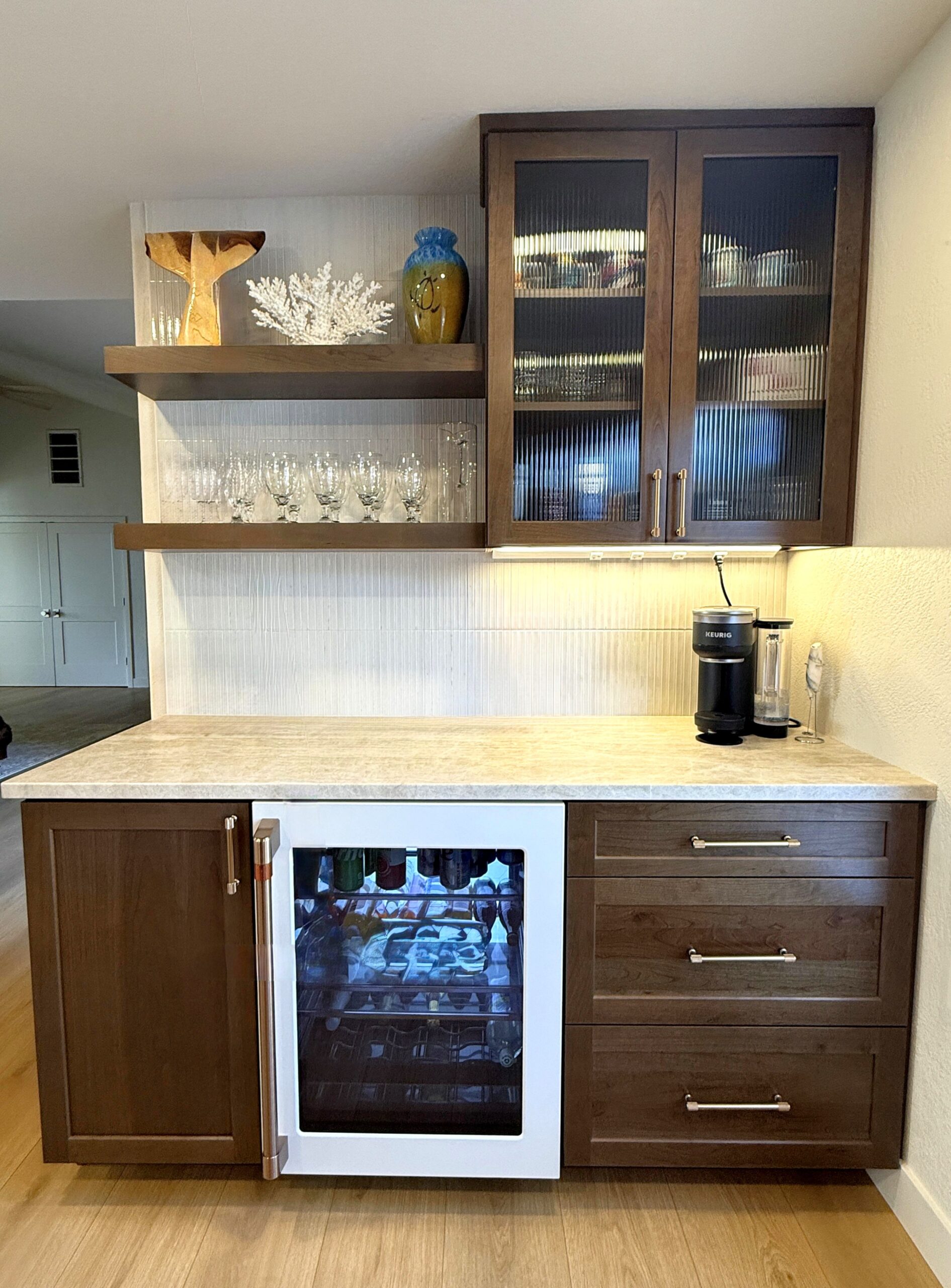 Built-in beverage station with dark wood cabinets, glass doors, floating shelves, and a wine refrigerator