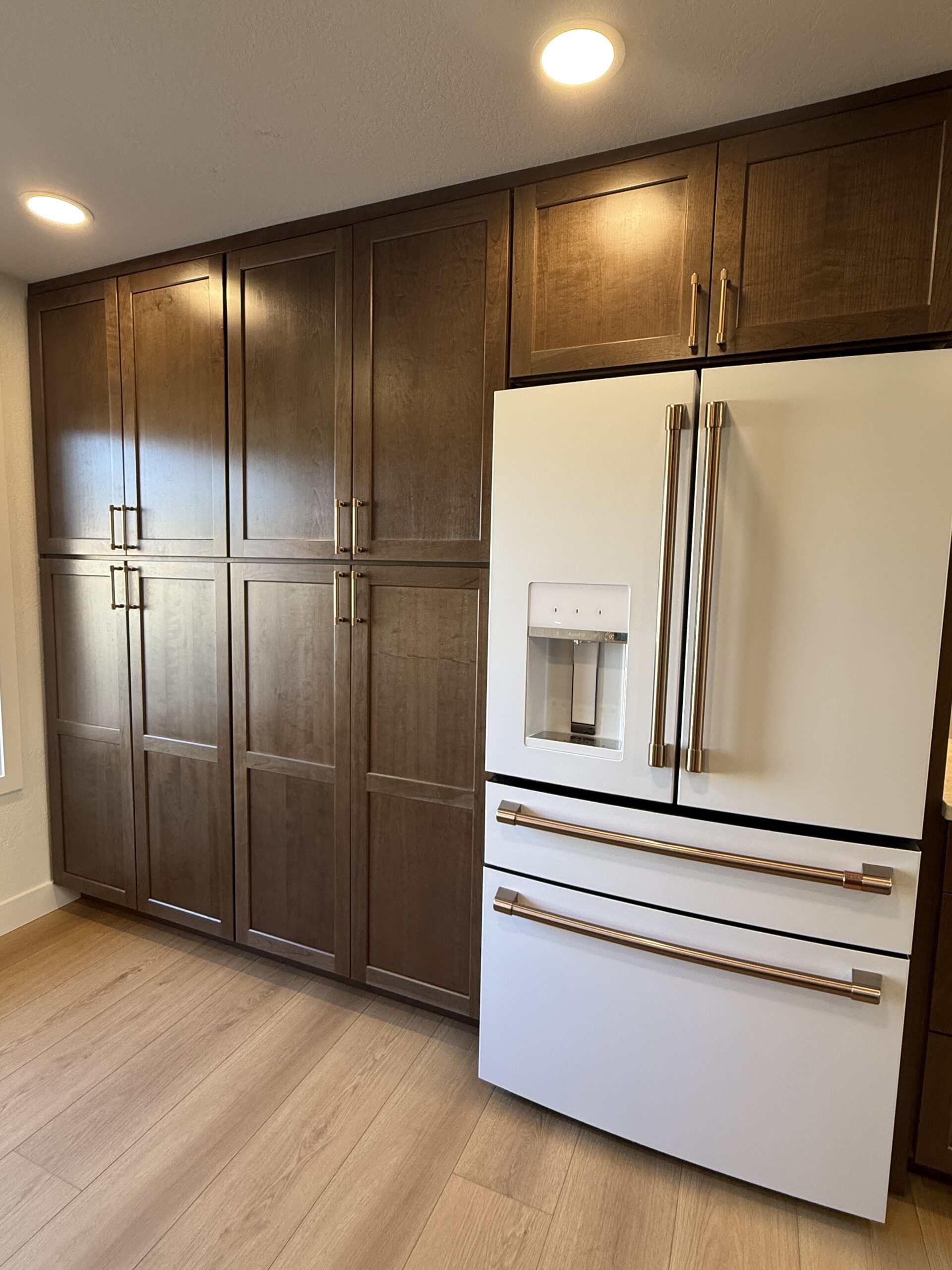Tall dark wood pantry cabinets surrounding a white French-door refrigerator