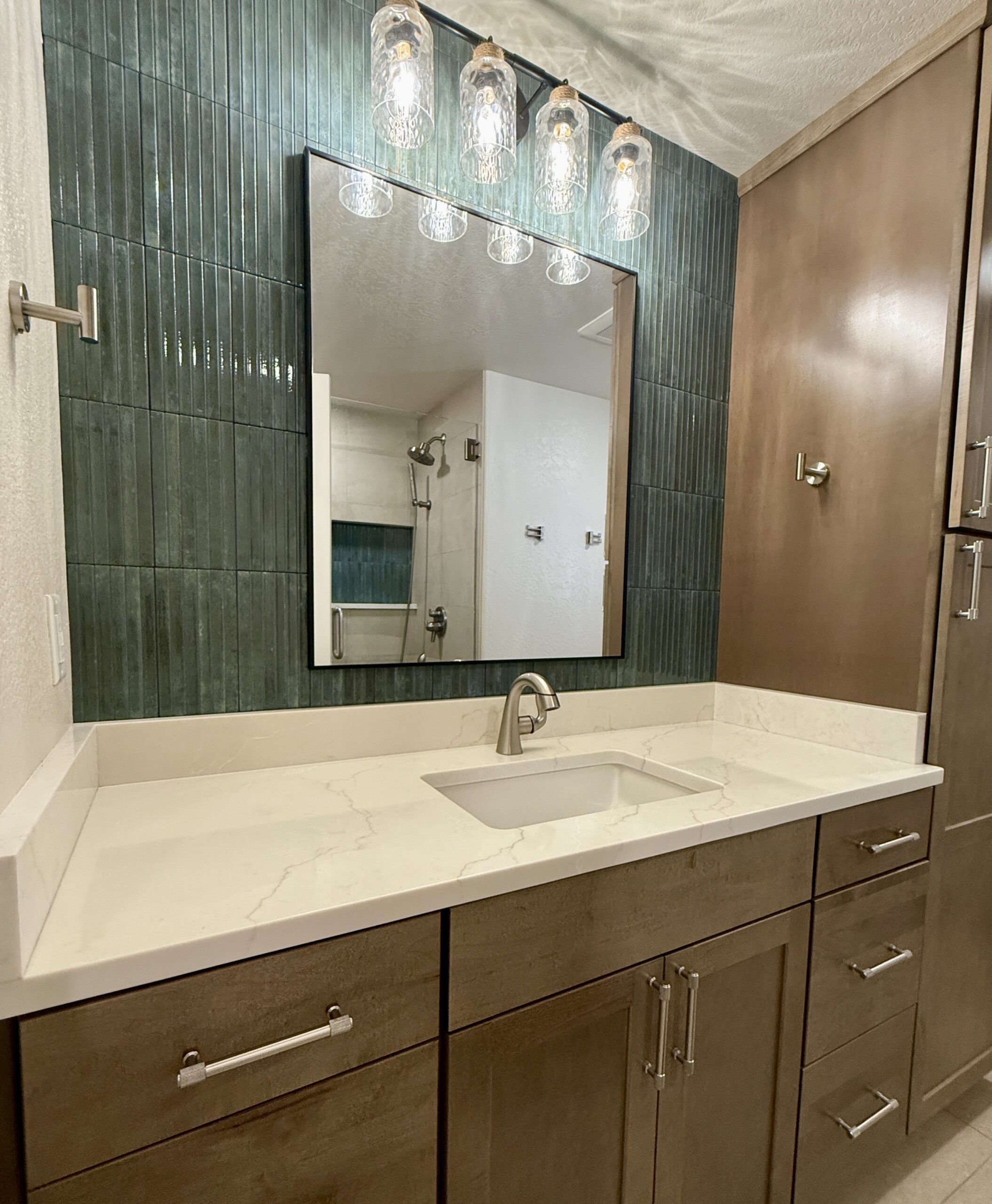 Single bathroom vanity with green vertical tile and wood cabinetry