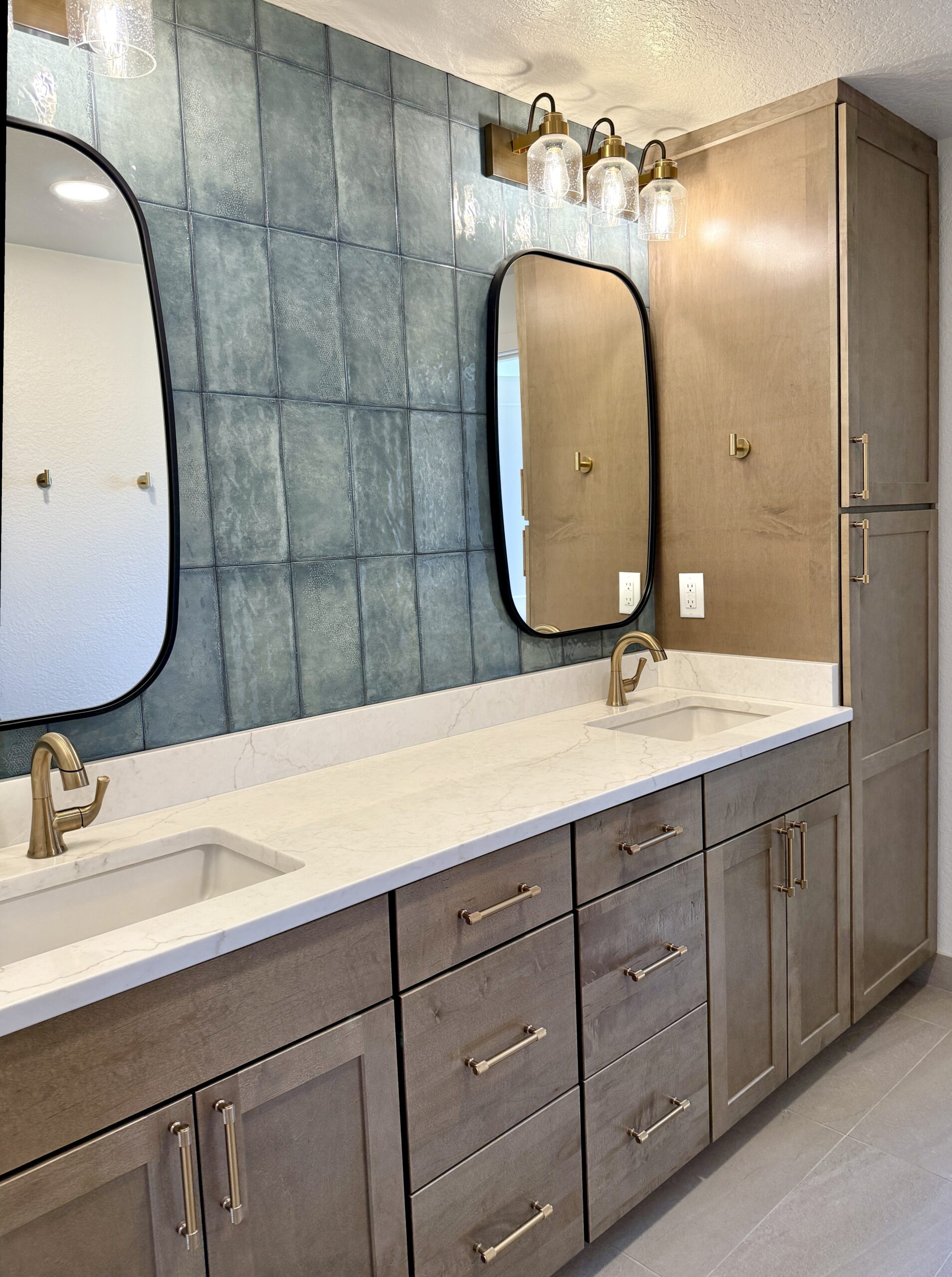 Double bathroom vanity with blue square tile and tall wood storage cabinets