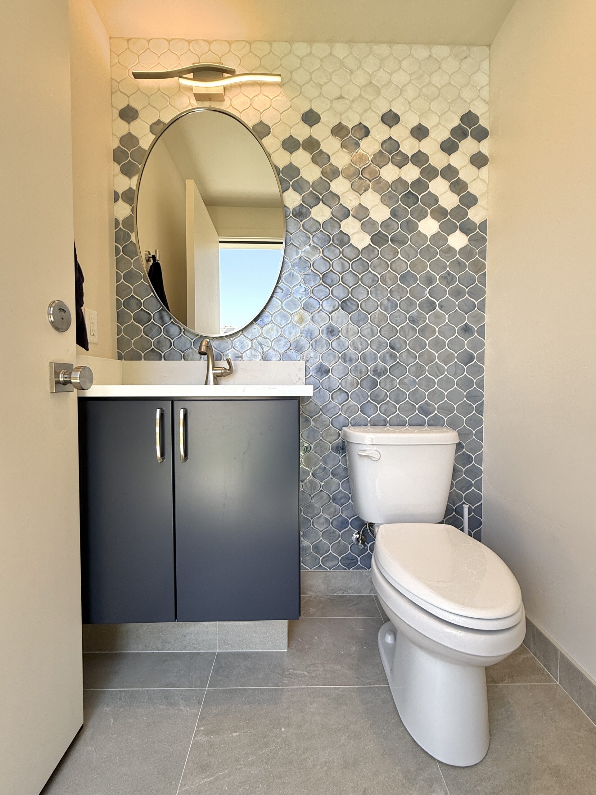 Compact powder room with a charcoal vanity and blue-gray mosaic tile accent wall